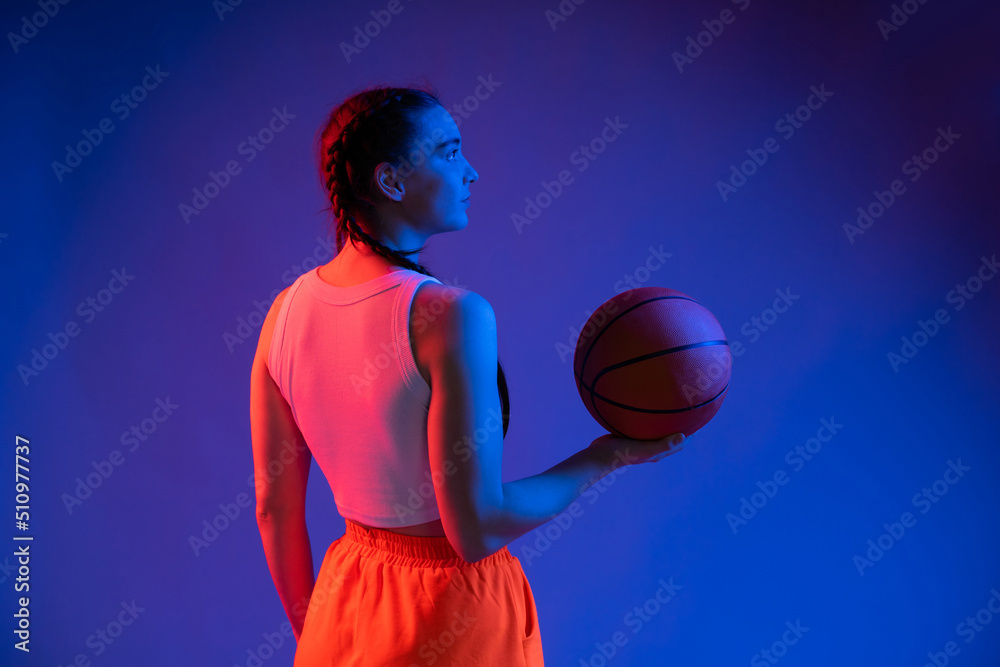 Fototapeta premium sports girl in the studio in shorts, a T-shirt with a basketball. blue background. sport concept. sports, healthy lifestyle