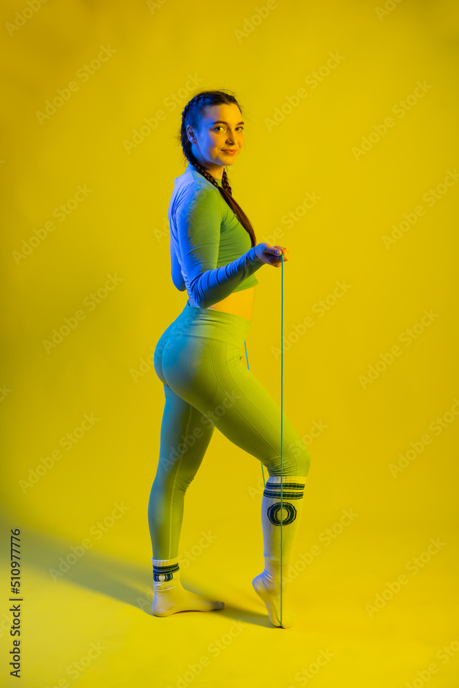 sports girl in the studio in fashionable sportswear. blue and yellow background. sport concept. sport, healthy lifestyle. fitness. colored light. beautiful model. strength and motivation.