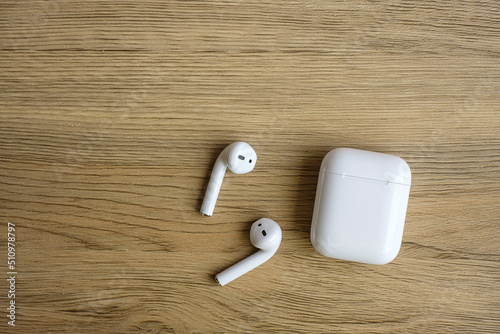 White wireless earphone or headphones on table for using with smartphone. Technology concept