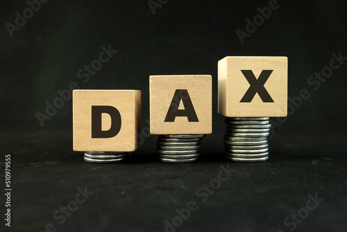 German stock market, Germany economy growth and recovery concept. DAX index in wooden blocks with increasing stack of coins in black background. photo