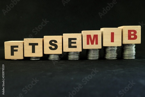 Italian Italy stock market economy growth and recovery concept. FTSE MIB index in wooden blocks with increasing stack of coins in black background. photo