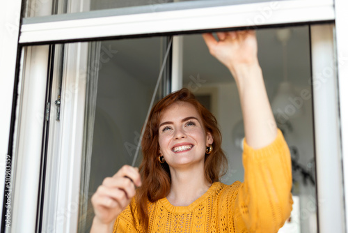 Φωτογραφία Woman hand hold retractable pleated insect screen holder to open or close the wi