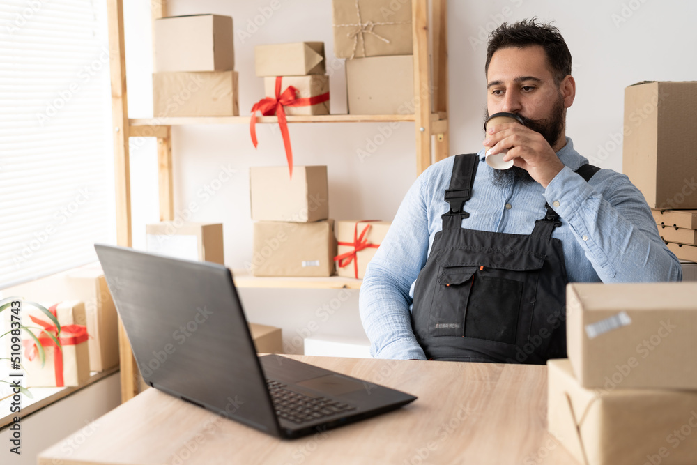 Small business aspiring indian entrepreneur drinking cofee, small and medium business freelance working in home office using computer, online marketing packaging box delivery, SME e-commerce Small business aspiring indian entrepreneur drinking cofee, small and medium business freelance working in home office using computer, online marketing packaging box delivery, SME e-commerce