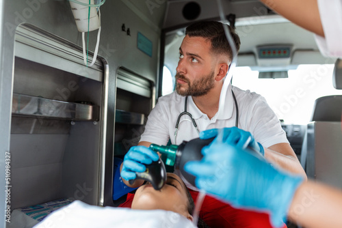 EMS Paramedics Team Provide Medical Help to Injured Patient on the Way to Healthcare Hospital. Emergency Care Assistant Using a Non-Invasive Ventilation Mask in an Ambulance. Close-up Shot. photo