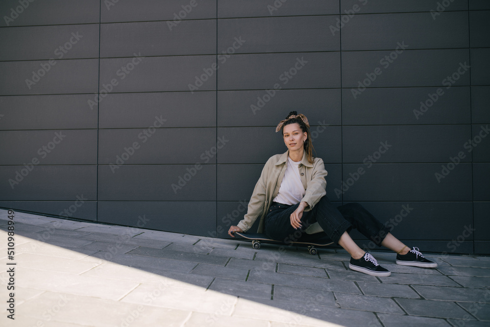 Young woman with braids style hair wearing casual clothes standing with skateboard on city street. Young woman with braids style hair wearing casual clothes standing with skateboard on city street.