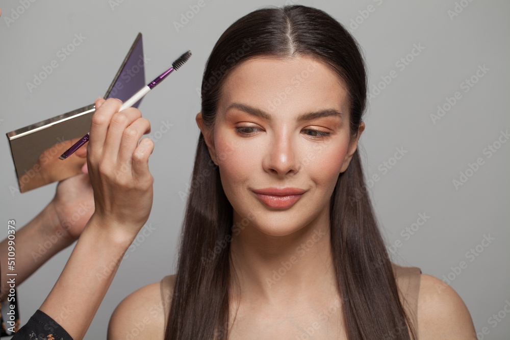 Beautiful female model face closeup and makeup artist hands with brush and eye shadow palette Beautiful female model face closeup and makeup artist hands with brush and eye shadow palette