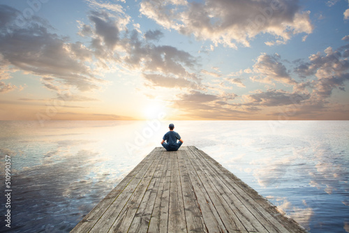 Man relaxing sitting on wooden jetty against sky clouds background