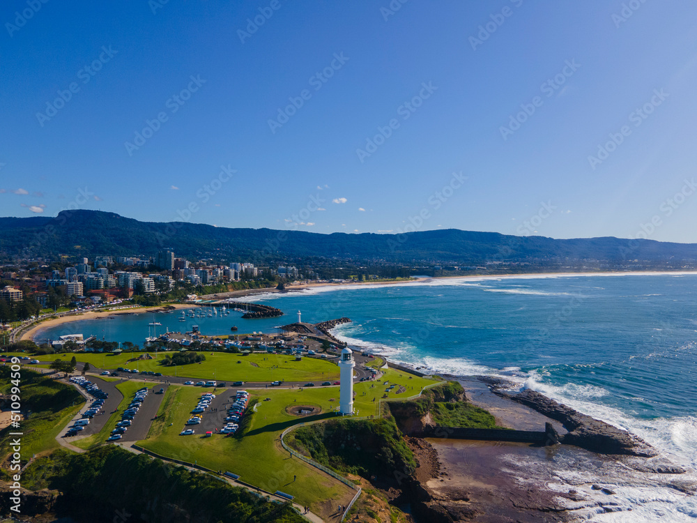 Low aerial drone view of Flagstaff Point Lighthouse at Wollongong on the New South Wales South Coast, Australia looking toward Wollongong North Beach on a sunny day   