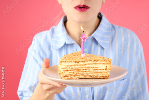 Girl wants to blow out the candle on pink background  close up