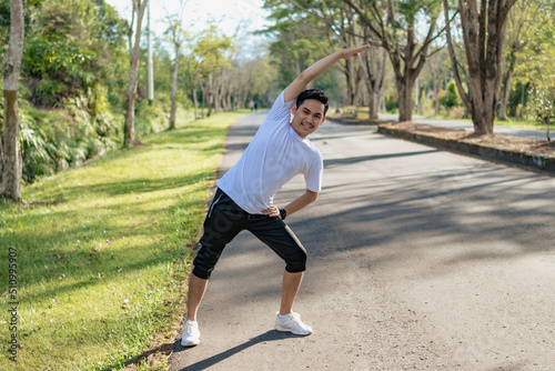 Young Asian man doing stretching exercise, preparing for running in the nature. Healthy lifestyle