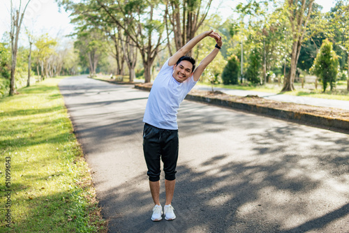 Young Asian man doing stretching exercise, preparing for running in the nature. Healthy lifestyle © Sewupari Studio