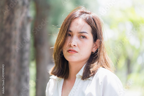 Head and shoulders portrait of serious young woman, sad woman in the park