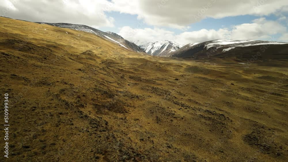 Landscape in the mountains. Mountain peaks with snow cover. Gray clouds. Aerial photography of the spring landscape in the wild. Landscape in the mountains. Mountain peaks with snow cover. Gray clouds. Aerial photography of the spring landscape in the wild.