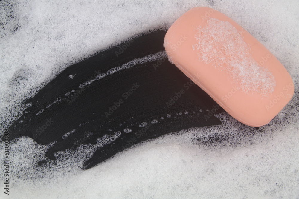 Fototapeta premium Pink soap bar and white soap foam on black background. 