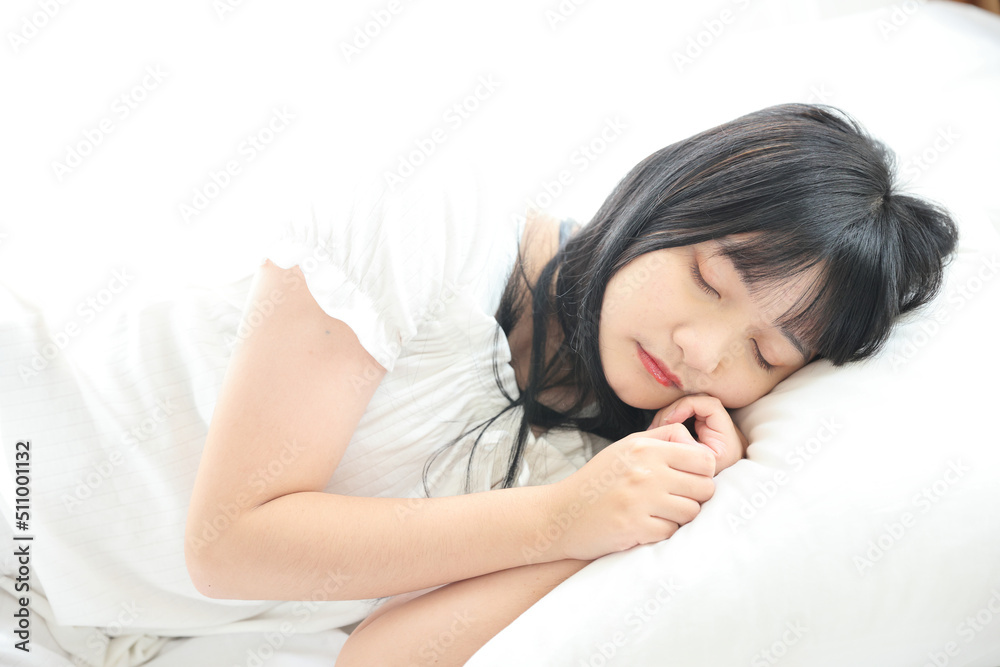 Beautiful young Asian woman sleeping on bed relaxing in the morning light with white room Beautiful young Asian woman sleeping on bed relaxing in the morning light with white room