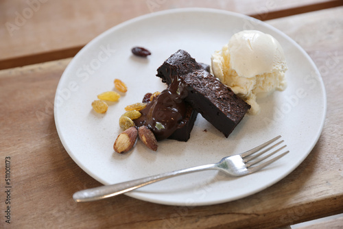 Brownies with dried fruits and ice cream on wood background