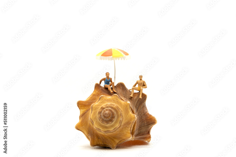 Naklejka premium Miniature people wearing swimsuit relaxing on seashells with white background , Summer Time concept