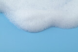 White soap or shampoo foam on blue background with copy space for text. 