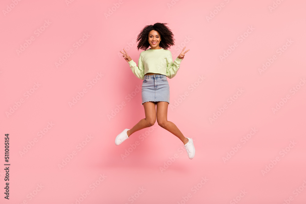 Full size photo of young cheerful girl jump up show fingers peace v-symbol isolated over pink color background
