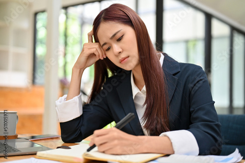 Stressed and bored asian female business employee sits at office desk. Upset, Failed