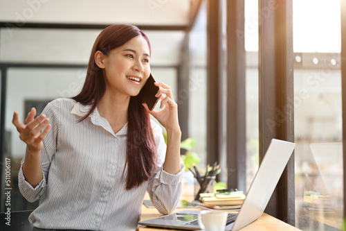 Confident asian businesswoman talking on the phone, making a business deal with business partner