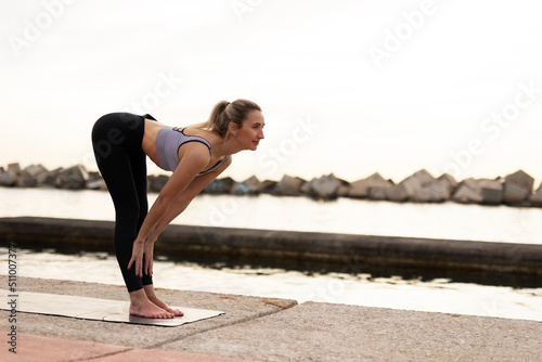 Beautiful young woman practising yoga outside. Fit woman doing yoga stretching exercises. © JustLife