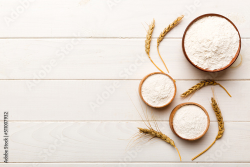Flat lay of Wheat flour in wooden bowl with wheat spikelets on colored background. world wheat crisis