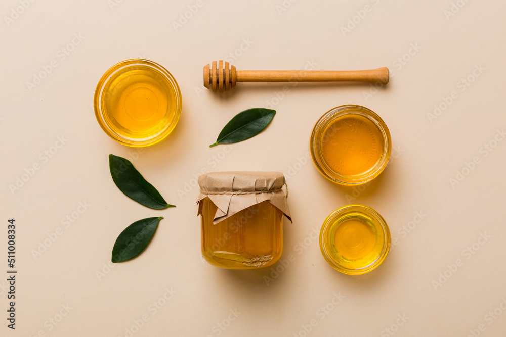 Honey jar with wooden honey dipper on white background top view with copy space. Delicious honey bottle