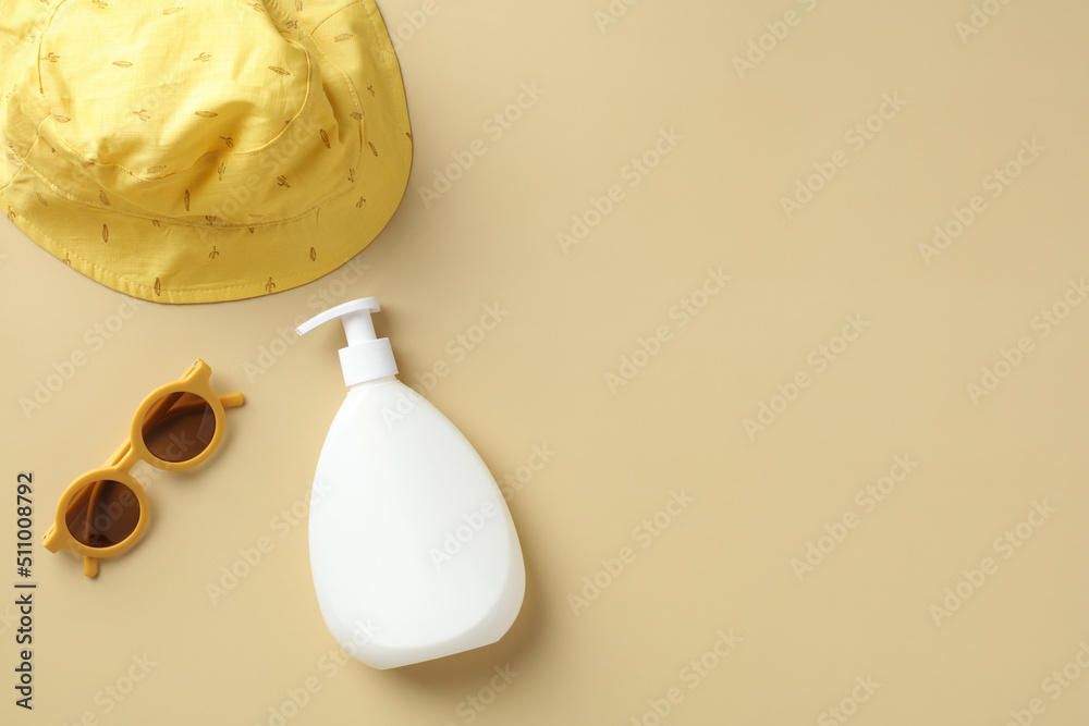 Suntan lotion, baby sunglasses, panama hat on beige background. Kids summer vacation concept. Flat lay, top view. Suntan lotion, baby sunglasses, panama hat on beige background. Kids summer vacation concept. Flat lay, top view.