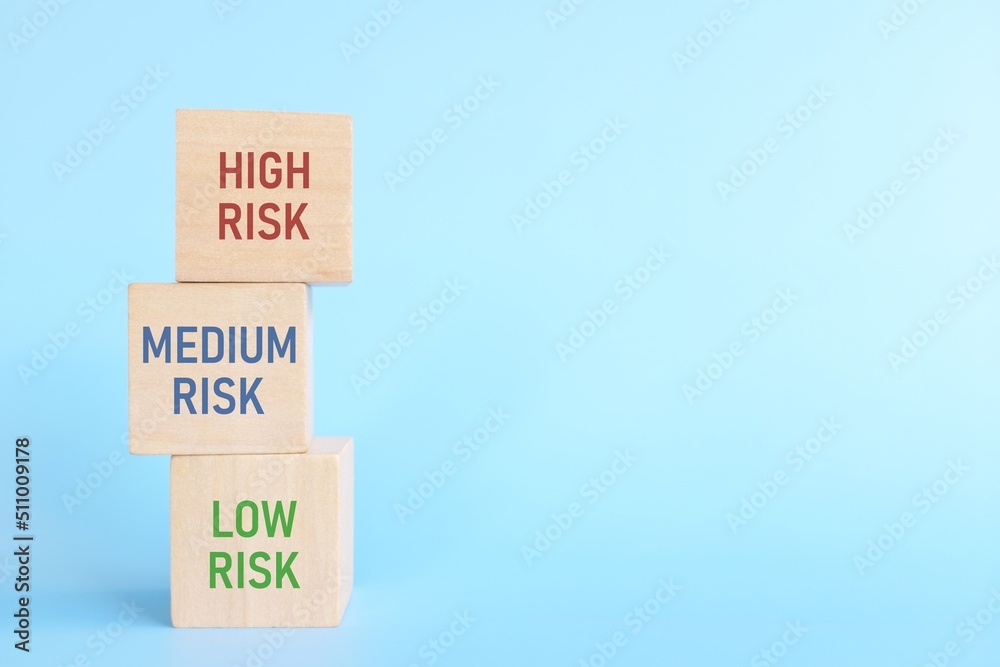Investment risk management, tolerance and planning and asset allocation and diversification concept. Wooden blocks with low, medium and high risk word with copy space.