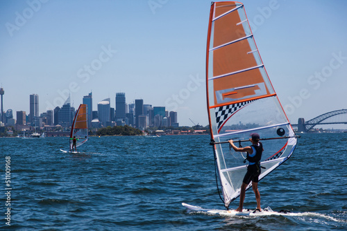 Windsurfing. Athletes windsurf in the bay against the backdrop of the city.