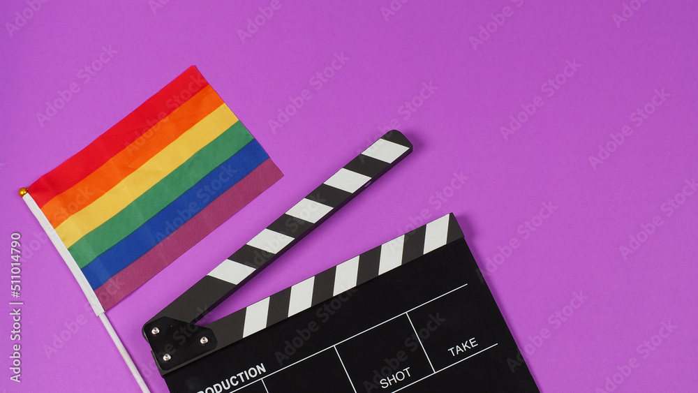 A rainbow flag and black clapperboard on purple background. LGBT CONCEPT..