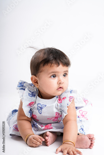 Indian baby girl sitting on white background.