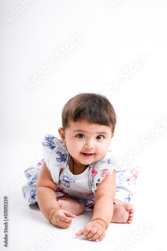 Indian baby girl sitting on white background.