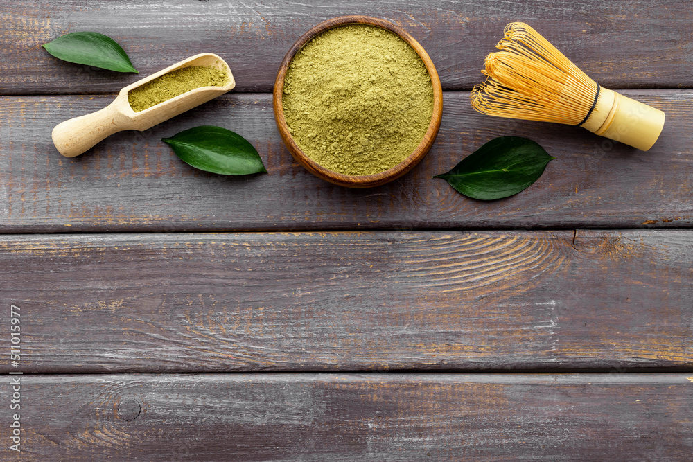 Green matcha powder in bowl with bamboo whisk