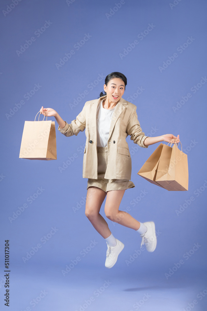 Woman carrying shopping bags and jumping on a purple background Woman carrying shopping bags and jumping on a purple background