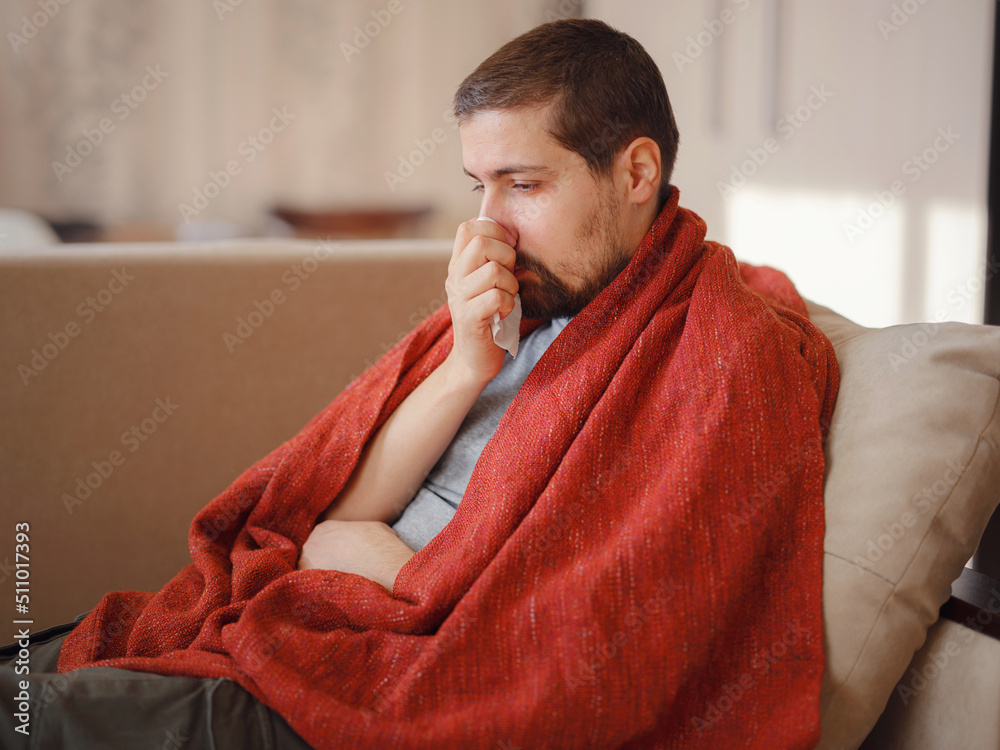Coronavirus. Sick man of corona virus lying down in sofa and recovery from illness in home. Blowing his nose. The concept of high temperatures. The person is seriously ill. Coronavirus. Sick man of corona virus lying down in sofa and recovery from illness in home. Blowing his nose. The concept of high temperatures. The person is seriously ill.