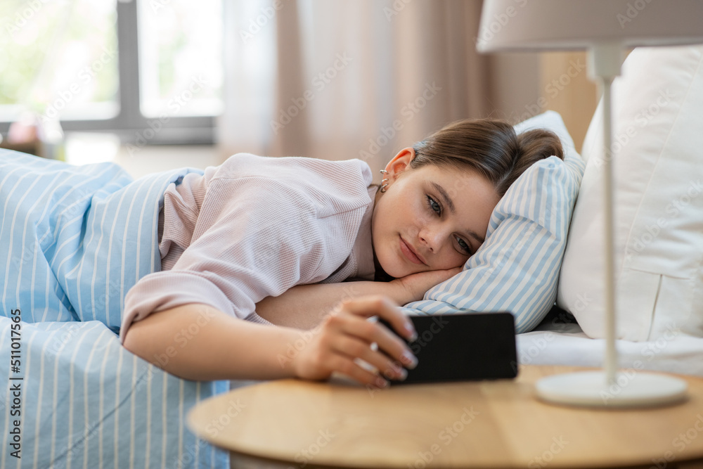 people, bedtime and rest concept - happy smiling teenage girl with smartphone lying in bed at home people, bedtime and rest concept - happy smiling teenage girl with smartphone lying in bed at home