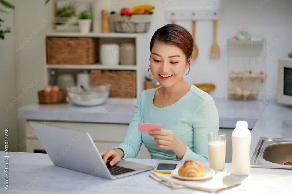 Young woman using laptop and credit card at home Young woman using laptop and credit card at home