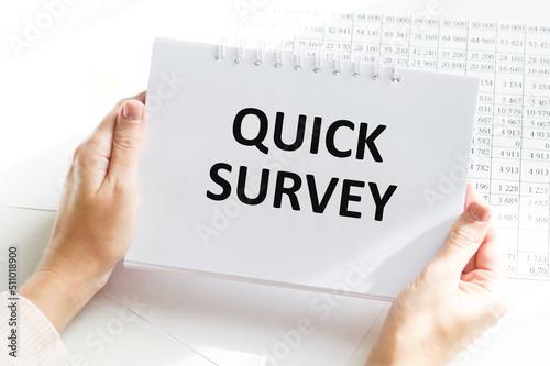 QUICK SURVEY text on a notebook in the hands of a businessman on the background of a desktop, a business concept
