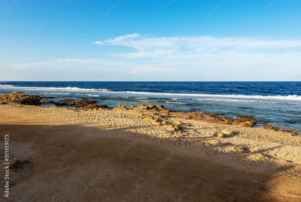 Sandy beach and beautiful seascape of Red Sea near Marsa Alam, Egypt, Africa. The waves breaking on the coral reef and the cliff.