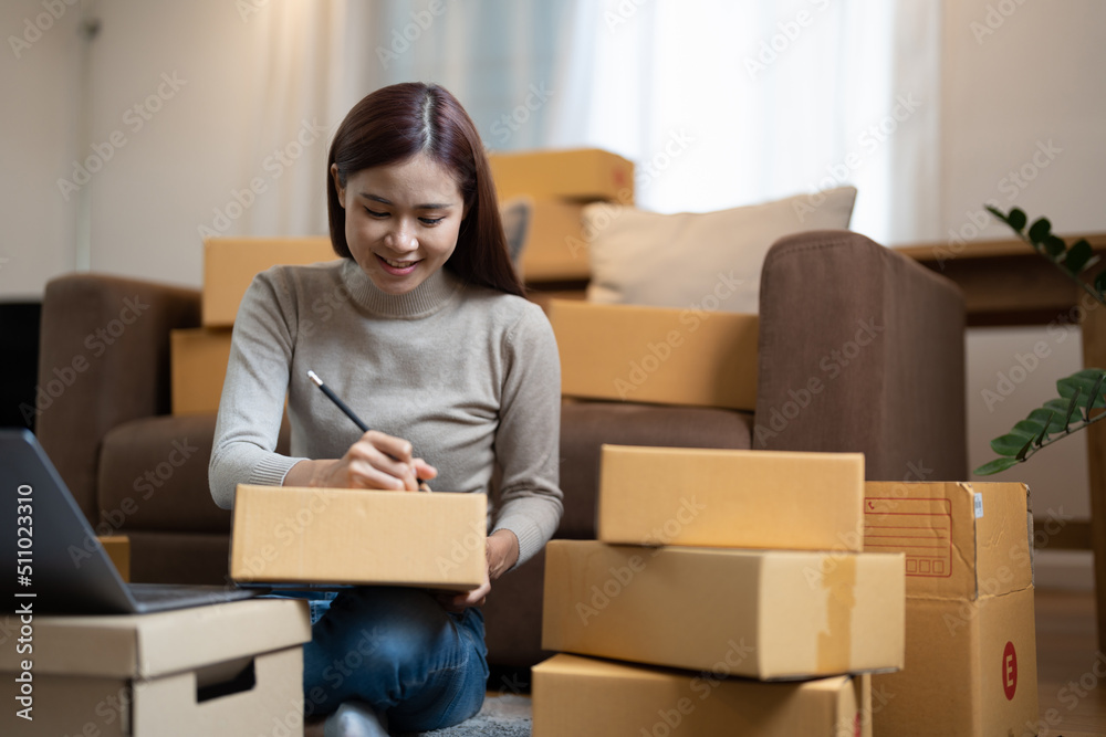 Shipping shopping online, young start up small business owner writing address on cardboard box at workplace.small business entrepreneur SME or freelance asian woman working at home Shipping shopping online, young start up small business owner writing address on cardboard box at workplace.small business entrepreneur SME or freelance asian woman working at home