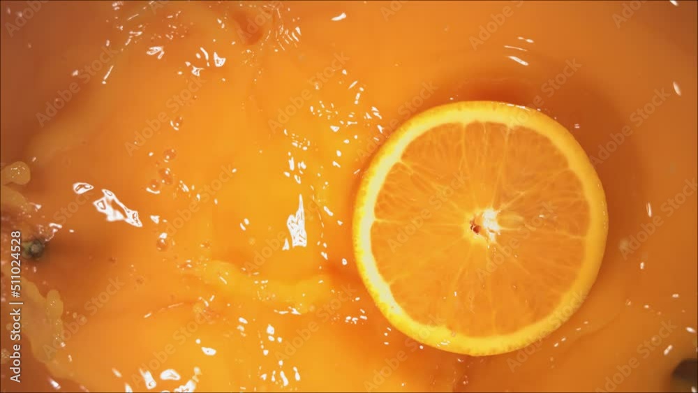 Orange Fruit falling on juice with splash and divided in half.