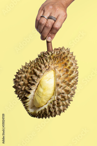 Hand holding Fresh durian on a yellow background.