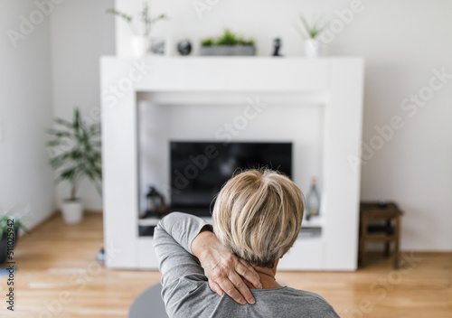 Senior woman in living room with neck pain
