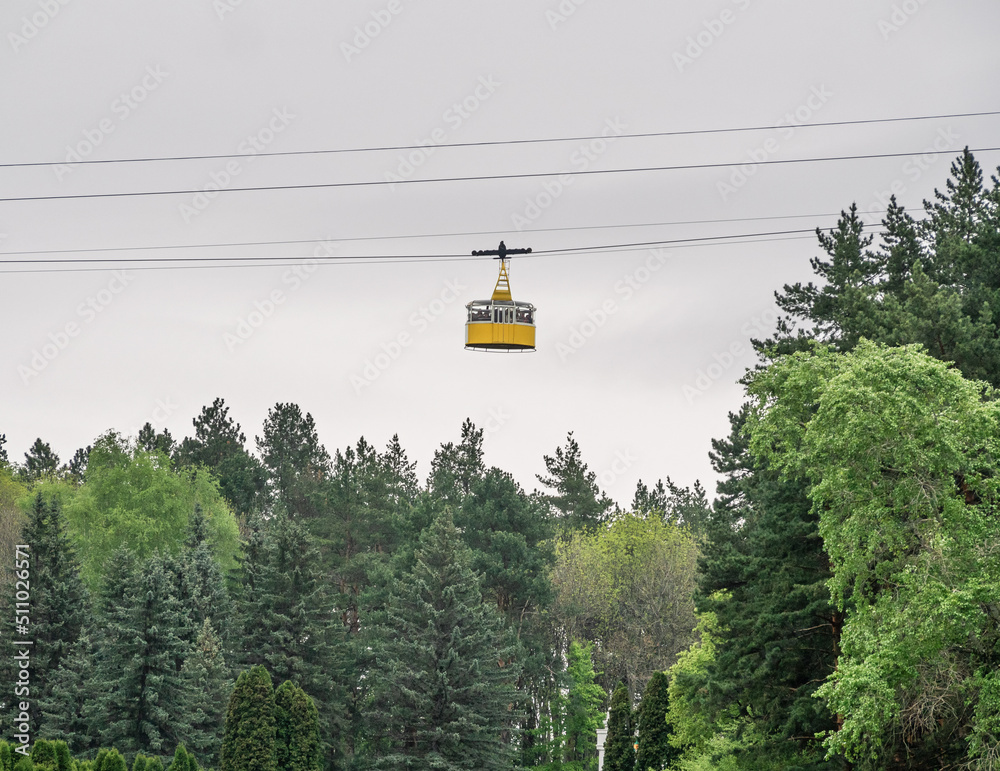 Cable car rising people over green forest
