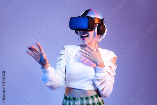 Young asian woman in white sweatshirt wearing black vr headset watching playing and hand touching on the purple color background. Metaverse concept. © CREATIVE WONDER