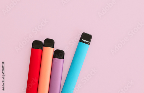 Layout of colorful disposable electronic cigarettes on a purple pink background. The concept of modern smoking, photo
