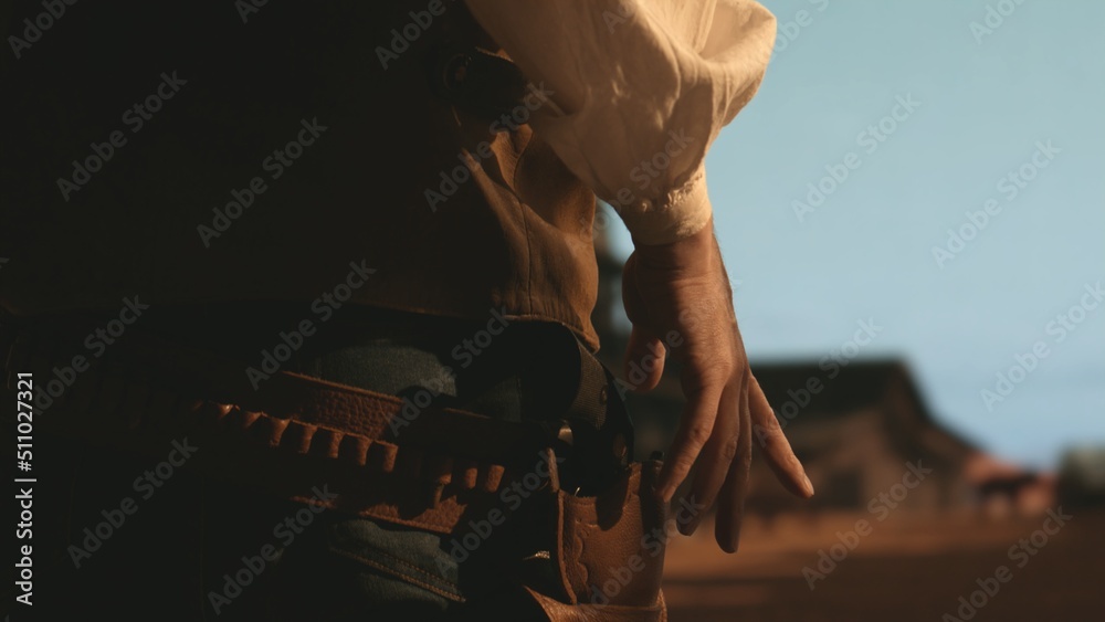 Cowboy preparing to draw his gun during standoff, CU on hands and holster. Spaghetti, macaroni western style cinematic footage - obrazy, fototapety, plakaty 