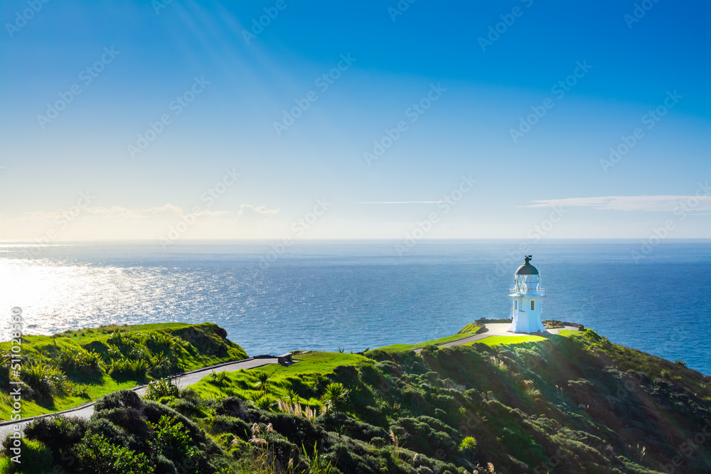 Stunning view of Cape Reinga Lighthouse glowing in sunlight. Famous tourist attraction at Cape Reinga, Far North, New Zealand.